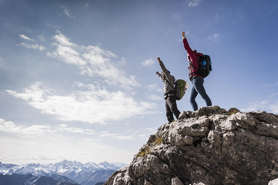 Germany, Bavaria, Oberstdorf, two hikers cheering on rock in alpine scenery #1 Photograph by Westend61
