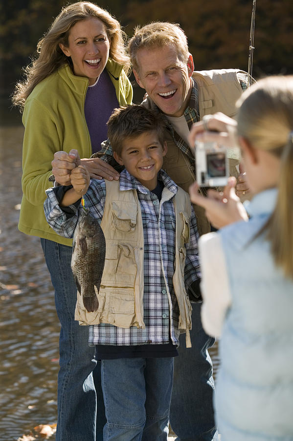 Girl taking photograph of family fishing #1 Photograph by Comstock Images
