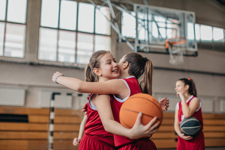 Girls basketball players hugging on court after match #1 Photograph by South_agency