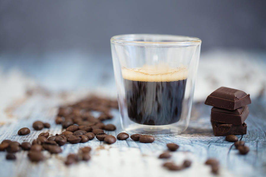 Glass cup of espresso, roasted coffee beans and dark chocolate on wood #1 Photograph by Westend61