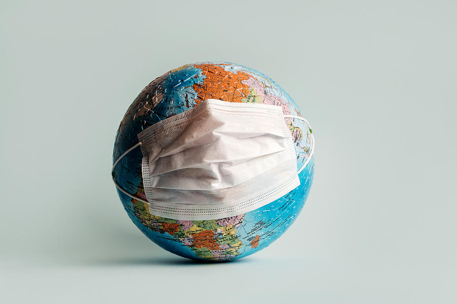 Globe made of jigsaw puzzles with a protective medical mask #1 Photograph by Fiordaliso