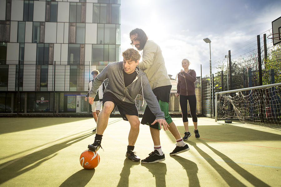 Group of adults playing football on urban football pitch #1 Photograph by Franek Strzeszewski