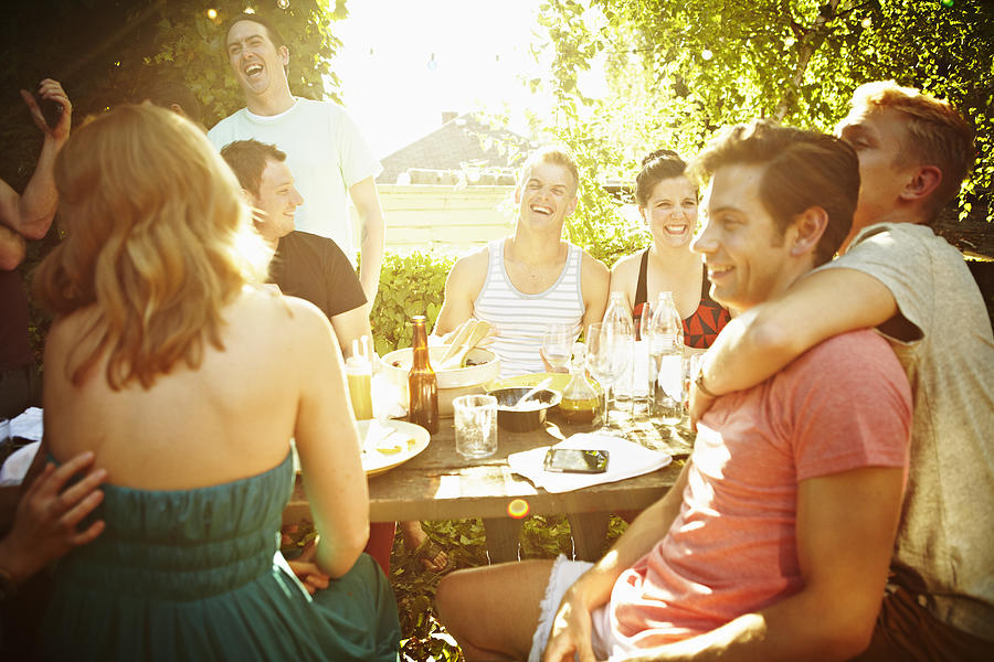 Group of friends sitting at table in backyard #1 Photograph by Thomas Barwick