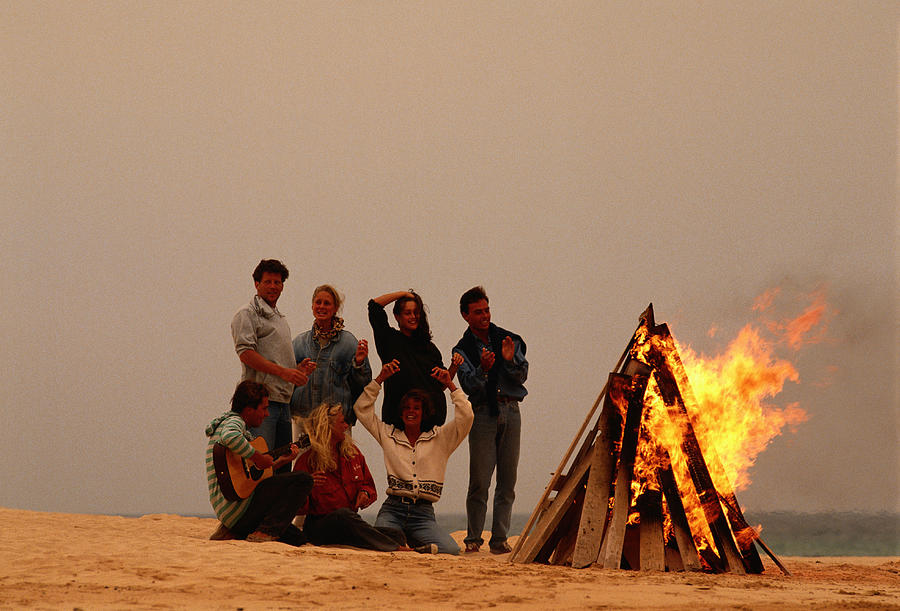 Group of people by campfire at beach #1 Photograph by David De Lossy