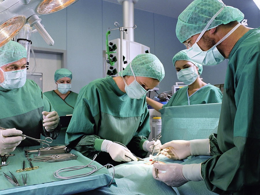 Group of surgeons working in operating theatre #1 Photograph by Jochen Sands