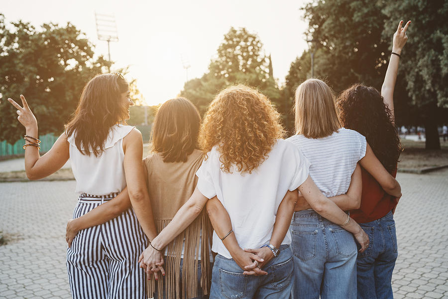 Group of women friends holding hands together against sunset Photograph by FilippoBacci