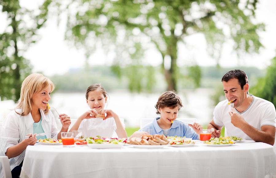 Happy family eating together outdoor. #1 Photograph by Skynesher