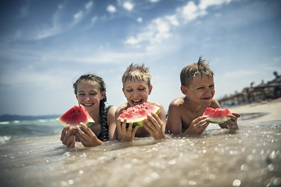Happy kids eating watermelon on the beach #1 Photograph by Imgorthand