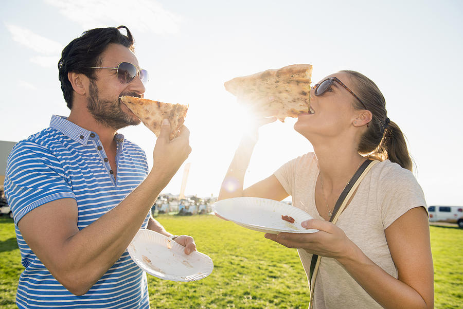 Hispanic couple eating pizza slices outdoors #1 Photograph by Jacobs Stock Photography Ltd