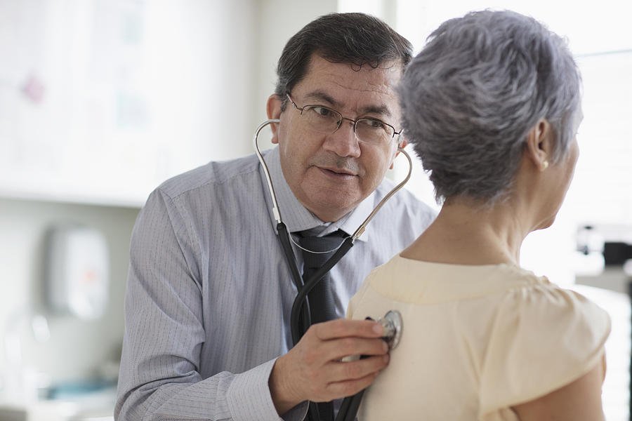 Hispanic doctor listening to back of patient with stethoscope #1 Photograph by Jose Luis Pelaez Inc