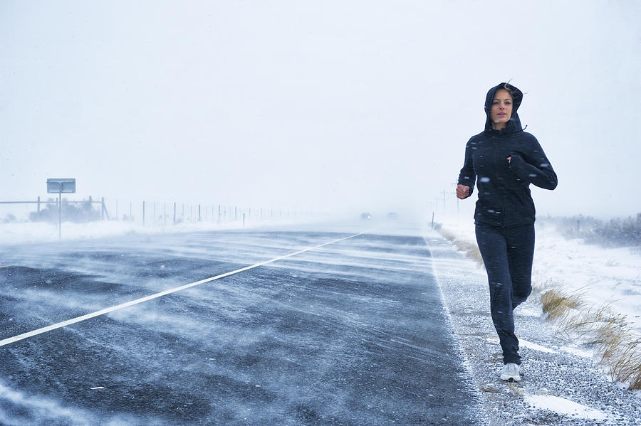 Hispanic woman jogging on snow covered road #1 Photograph by Jacobs Stock Photography Ltd