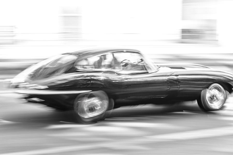 Jaguar E-Type driving at high speed on a road through a forest #1 Photograph by Sjo
