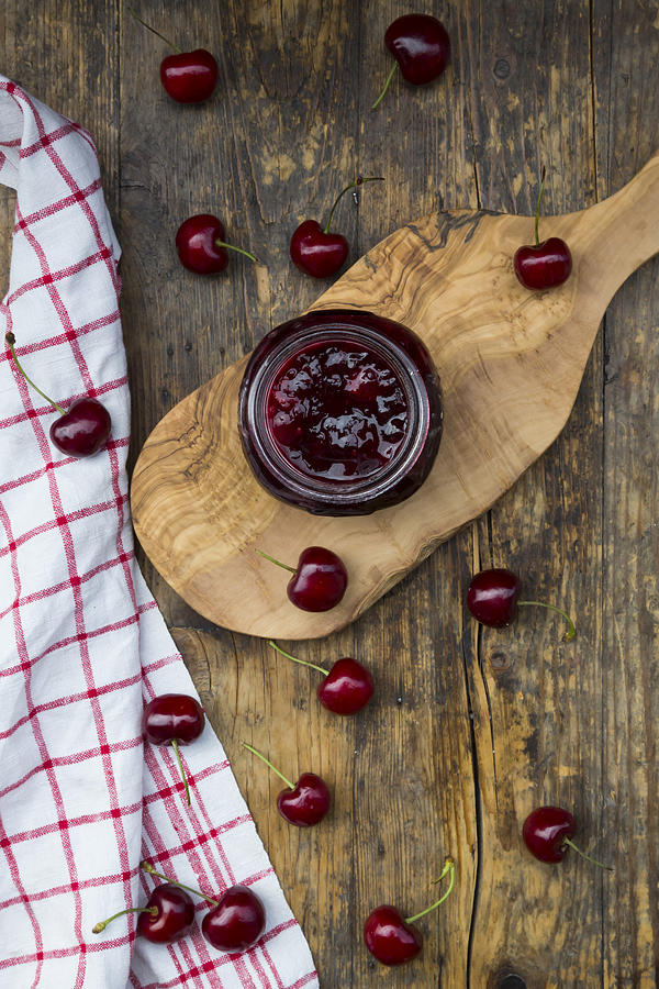 Jar of homemade cherry jam and cherries on wood #1 Photograph by Larissa Veronesi