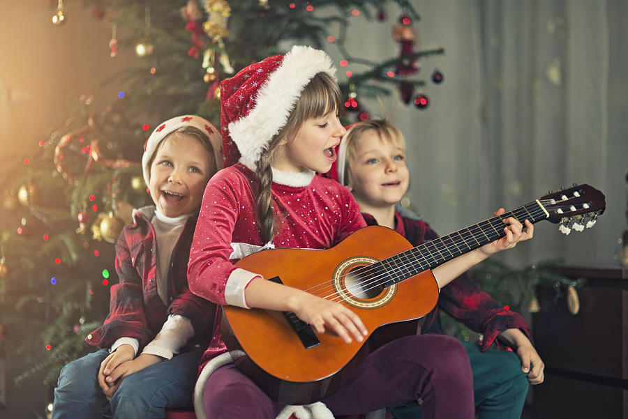 Kids singing carols near the christmas tree #1 Photograph by Imgorthand