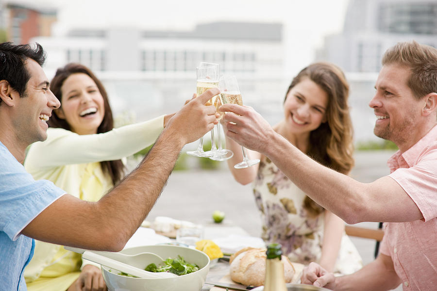 Laughing couples toasting with Champagne outdoors #1 Photograph by Paul Bradbury