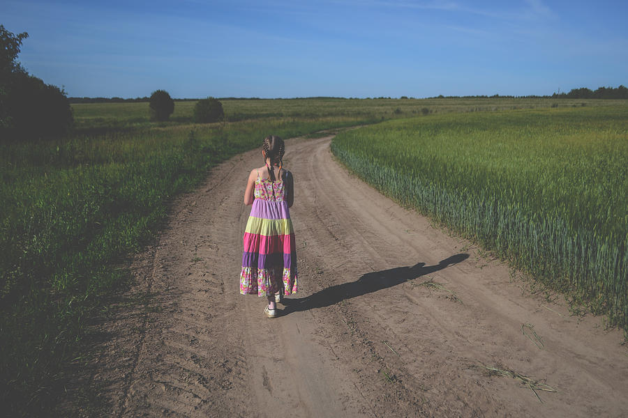 Little girl in dress walking along the road #1 Photograph by Alekseyliss