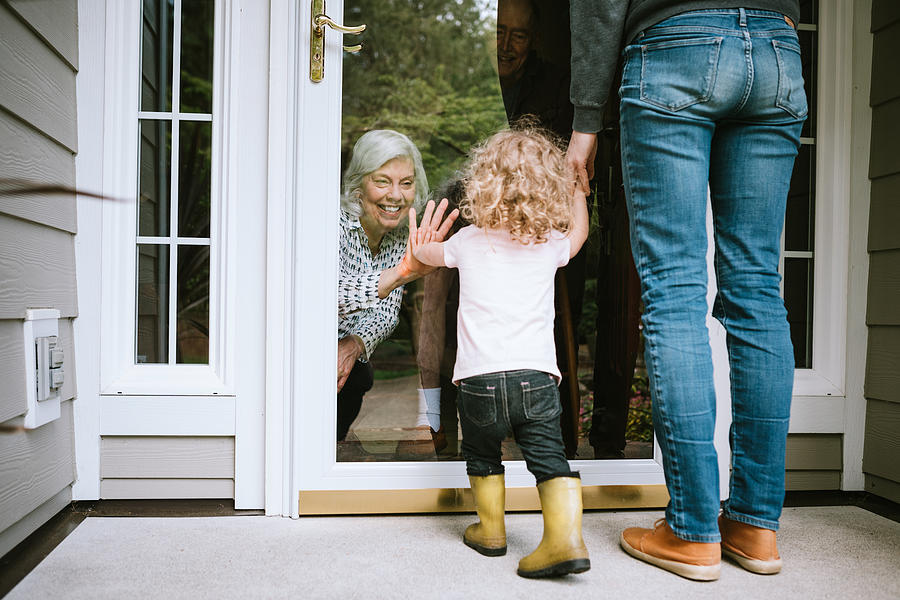Little Girl Visits Grandparents Through Window #1 Photograph by RyanJLane