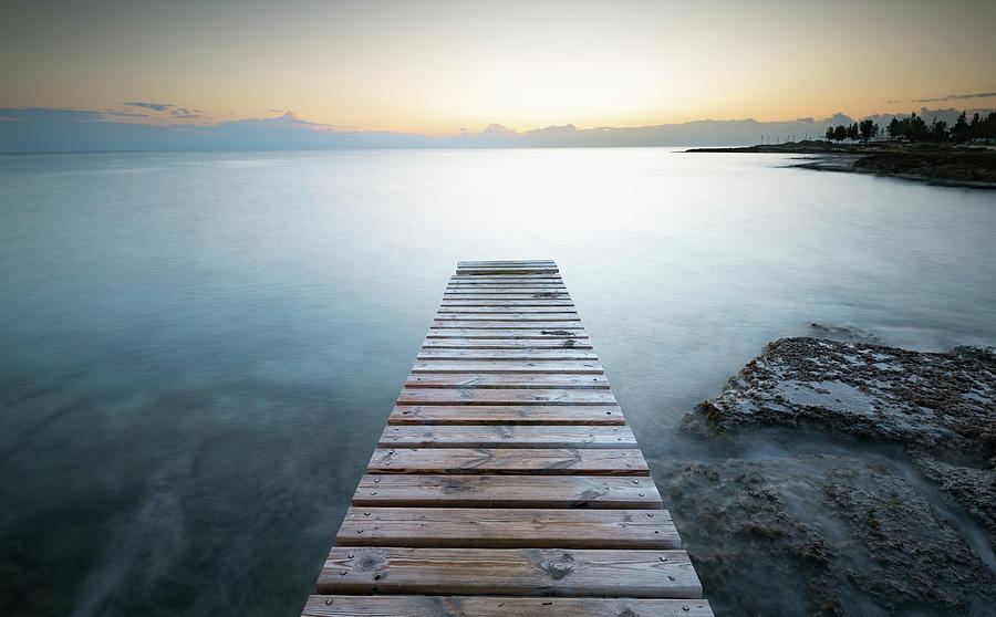 Long wooden pier in the sea at sunrise. #1 Photograph by Michalakis Ppalis