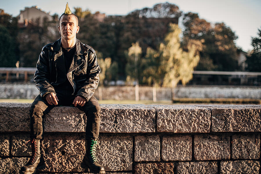 Male punk person in combat boots sitting outdoors in city #1 Photograph by South_agency
