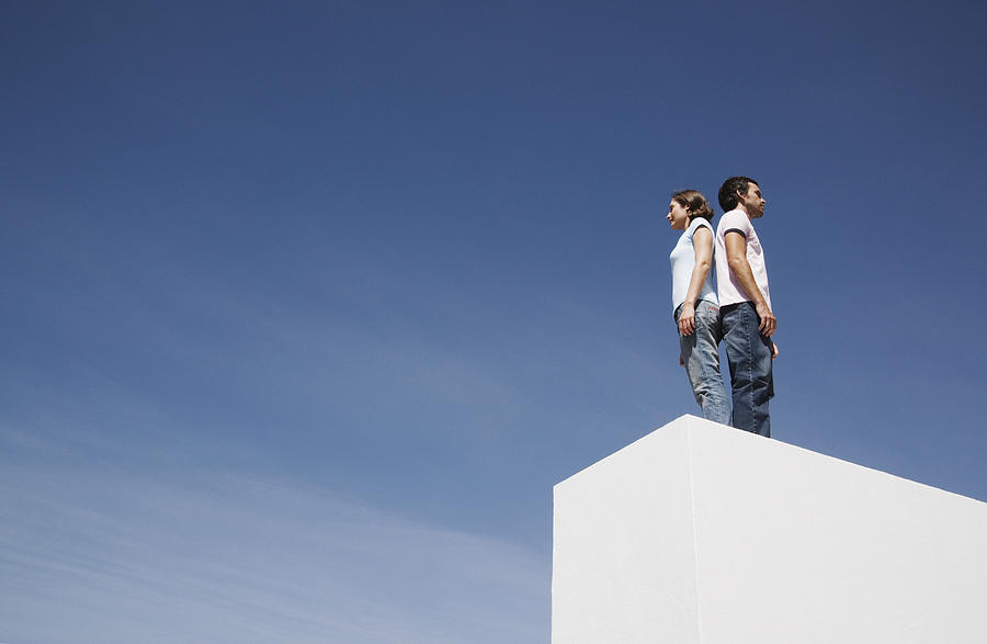 Man and woman standing on box back to back outdoors with blue sky #1 Photograph by Martin Barraud