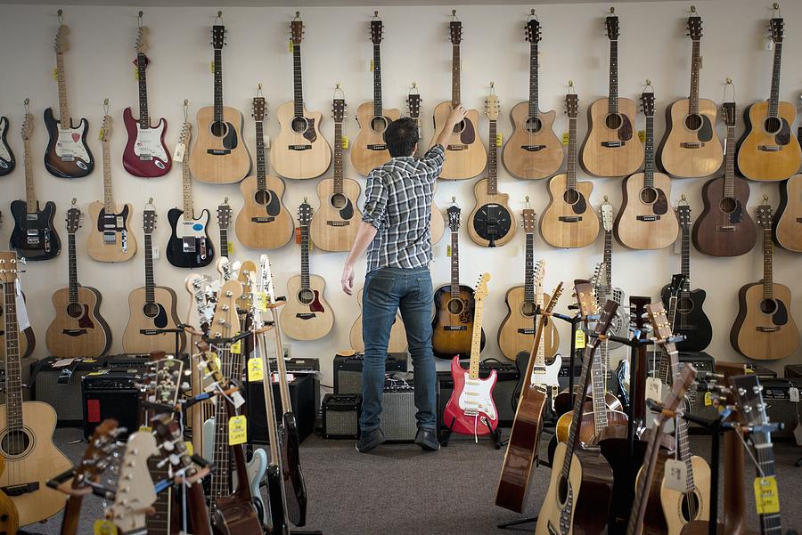 Man choosing guitar in shop #1 Photograph by Hiya Images/Corbis
