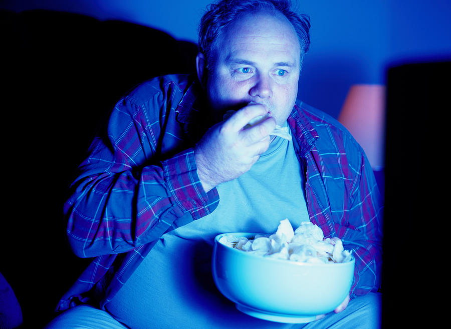 Man Eating Potato Chips and Watching Television #1 Photograph by Ryan McVay