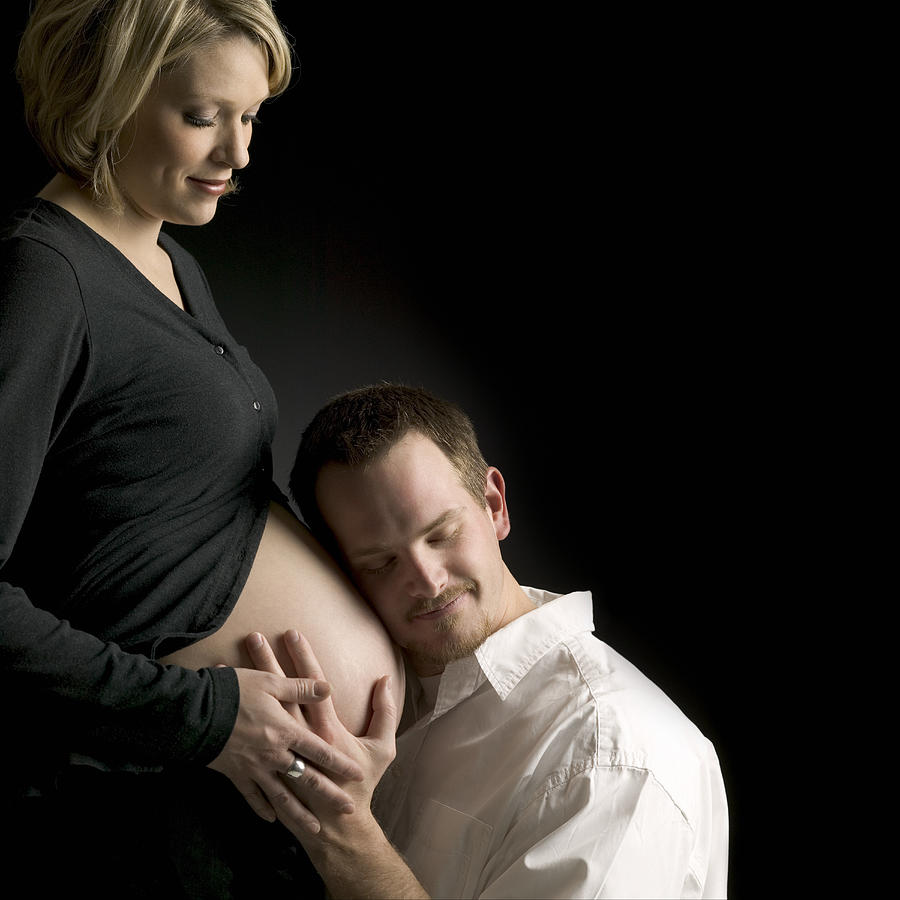 Man feeling a pregnant womans stomach #1 Photograph by Photodisc