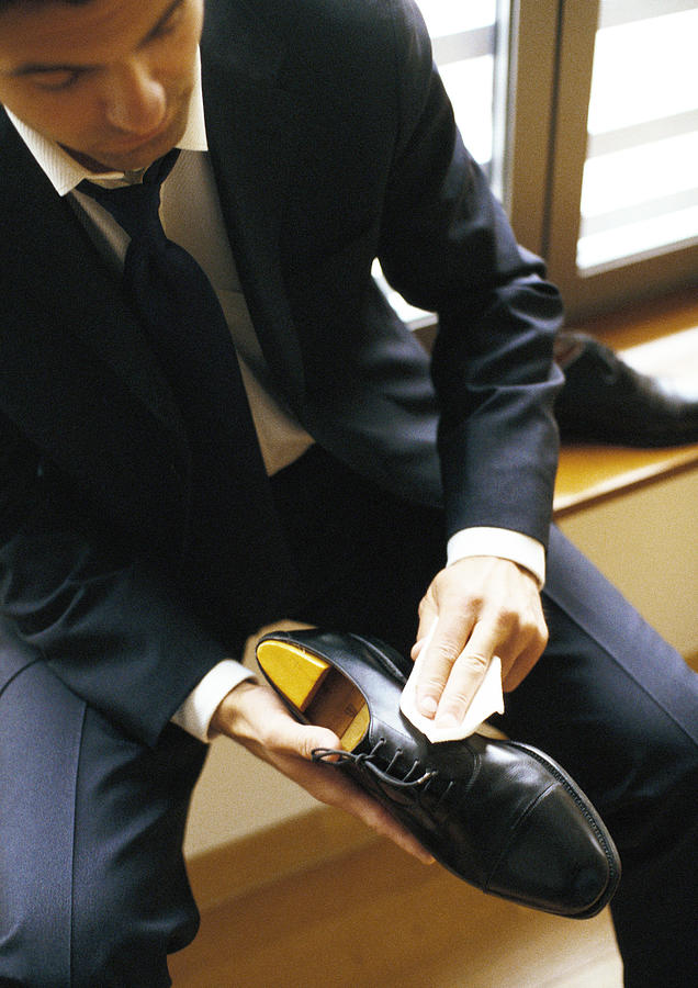 Man in suit polishing shoe, close-up #1 Photograph by John Dowland