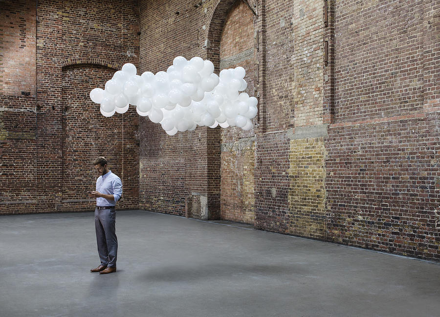 Man in warehouse with cloud of balloons above head #1 Photograph by Anthony Harvie