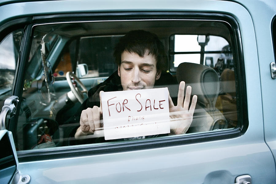 Man putting up  for sale sign in car, view through window #1 Photograph by Dimitri Otis