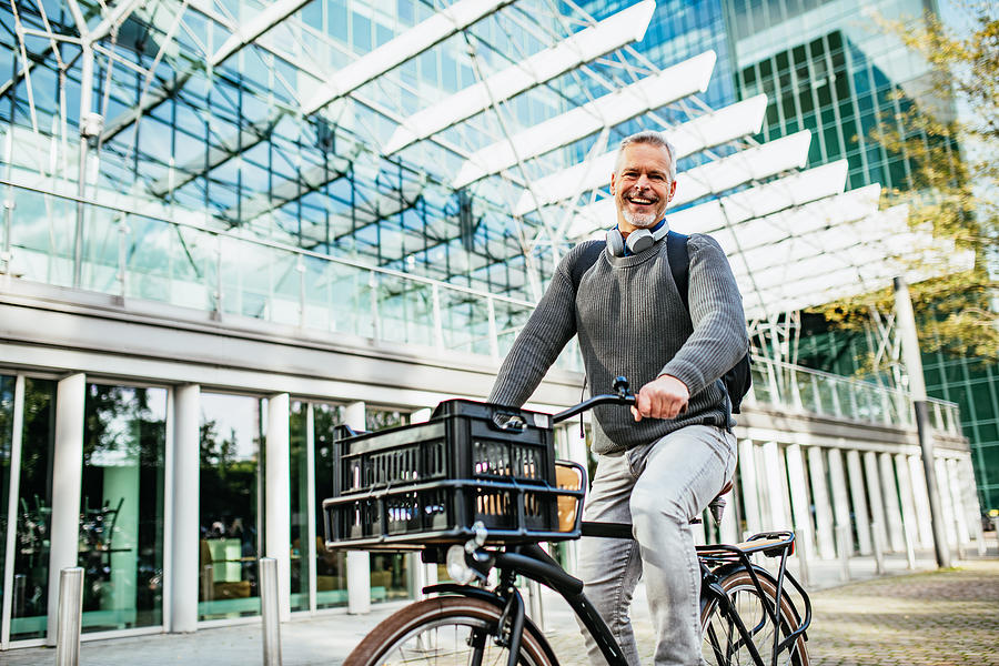 Mature gray hair man riding bicycle and contributes to eco-friendly environment #1 Photograph by Drazen_