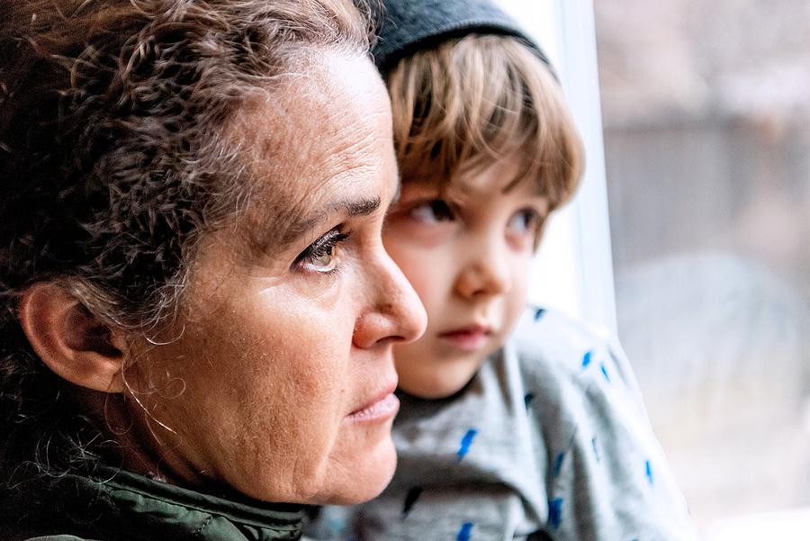 Mature woman posing with her son, very sad looking through window worried about loss of her job due Covid-19 pandemic #1 Photograph by Juanmonino