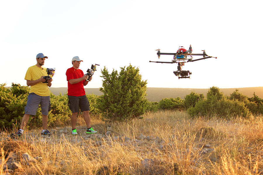 Men flying drone at sunset #1 Photograph by Simonkr