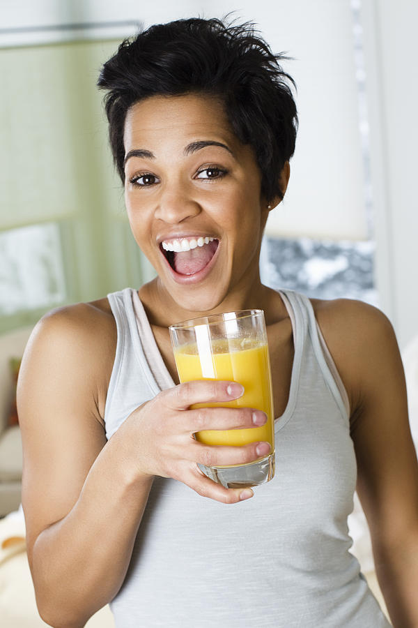 Mid adult woman holding a glass of orange juice #1 Photograph by SuperStock \ Jon Feingersh Photography