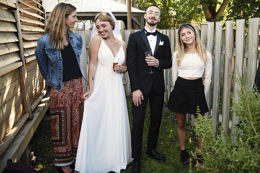 Millennial newlywed couple posing with family members in backyard. #1 Photograph by Martinedoucet
