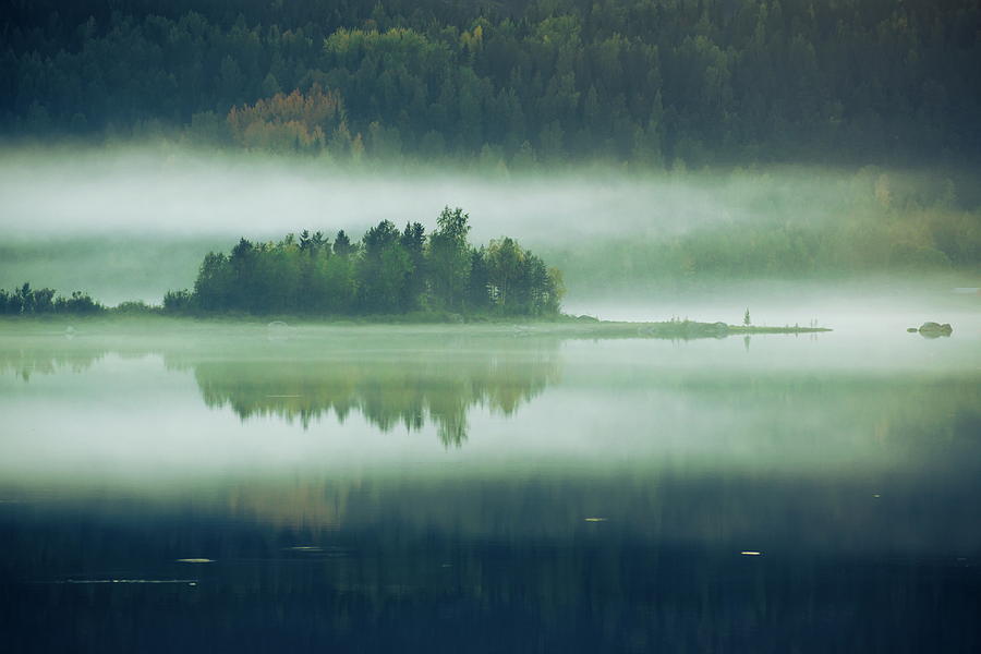MIst  rising over a small wooded island is reflected in a glassy #1 Photograph by Ulrich Kunst And Bettina Scheidulin