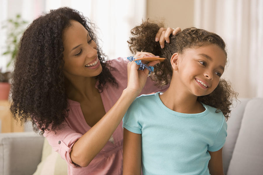 Mixed race mother brushing daughters hair #1 Photograph by Jose Luis Pelaez Inc