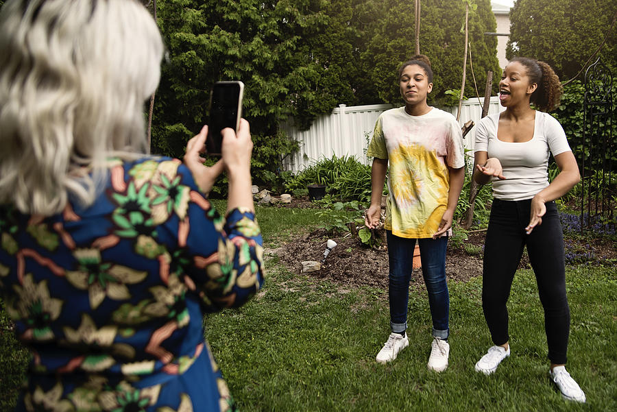 Mixed-race sisters being filmed by mother in backyard. #1 Photograph by Martinedoucet