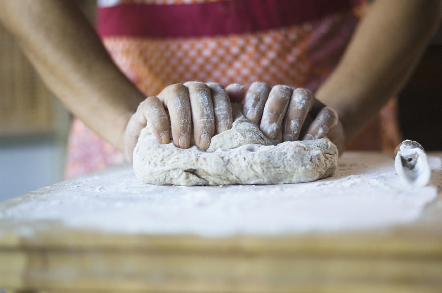 Mixed race woman kneading dough in kitchen #1 Photograph by Karin Dreyer