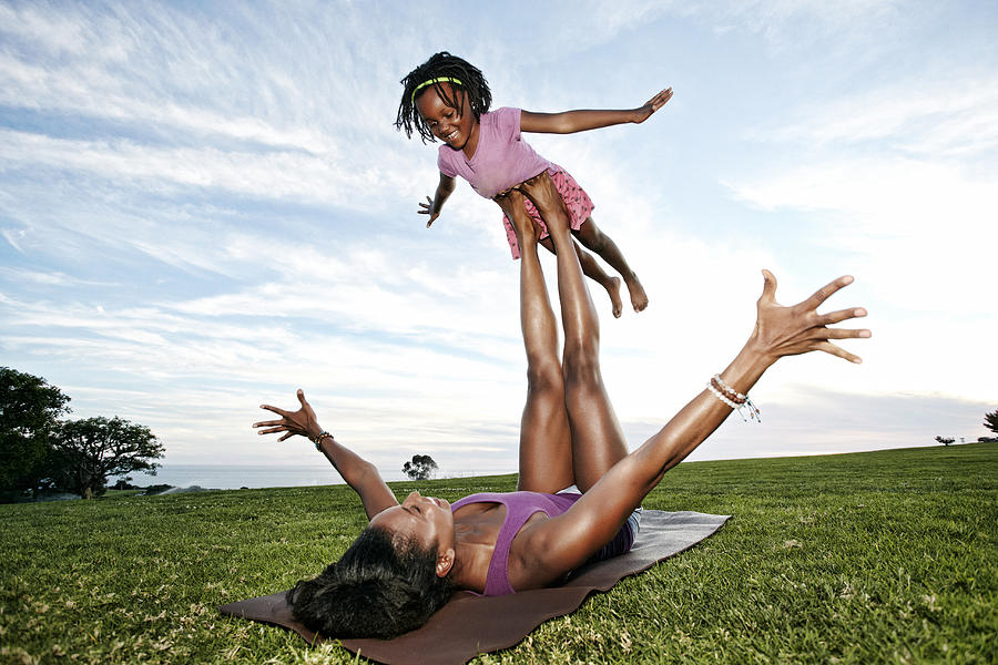 Mother balancing daughter on legs in park #1 Photograph by Peathegee Inc