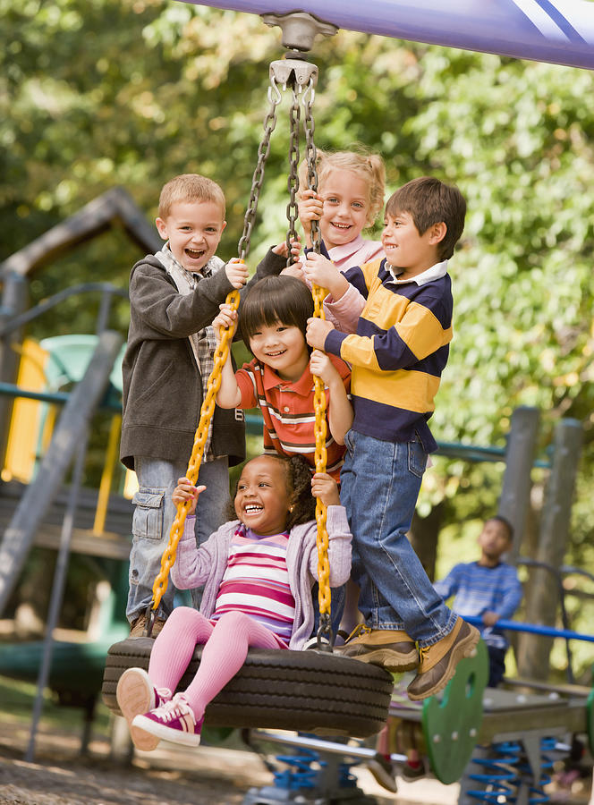 Multi-ethnic children playing on tire swing #1 Photograph by Ariel Skelley