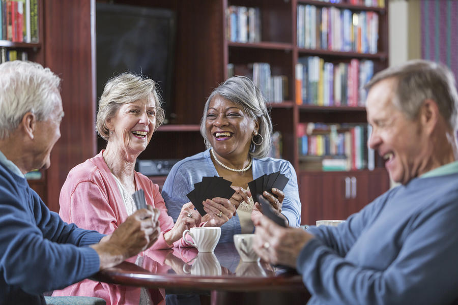 Multiracial group of seniors talking, playing card game #1 Photograph by Kali9