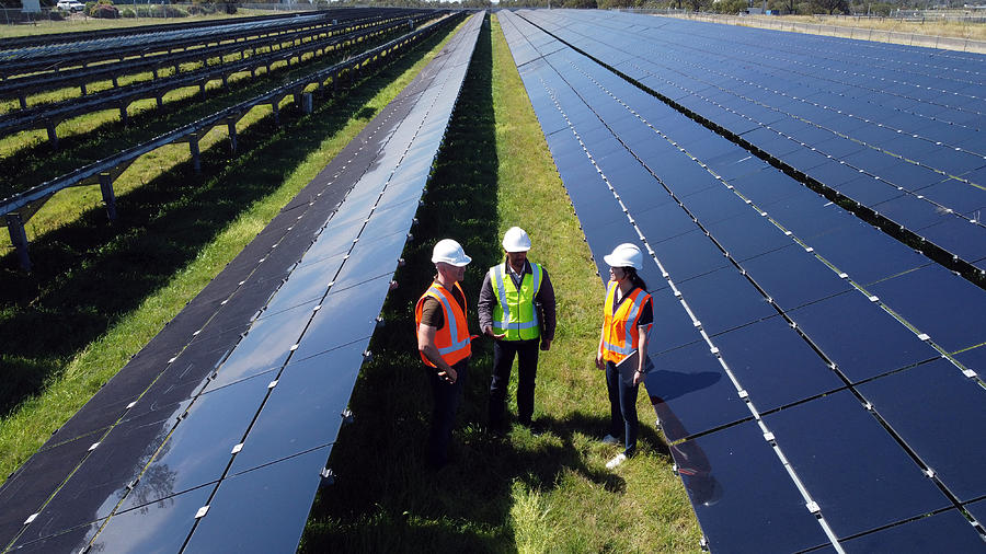 Multiracial Group Of Three Engineers Surrounded By Solar Panels Photograph by Thurtell