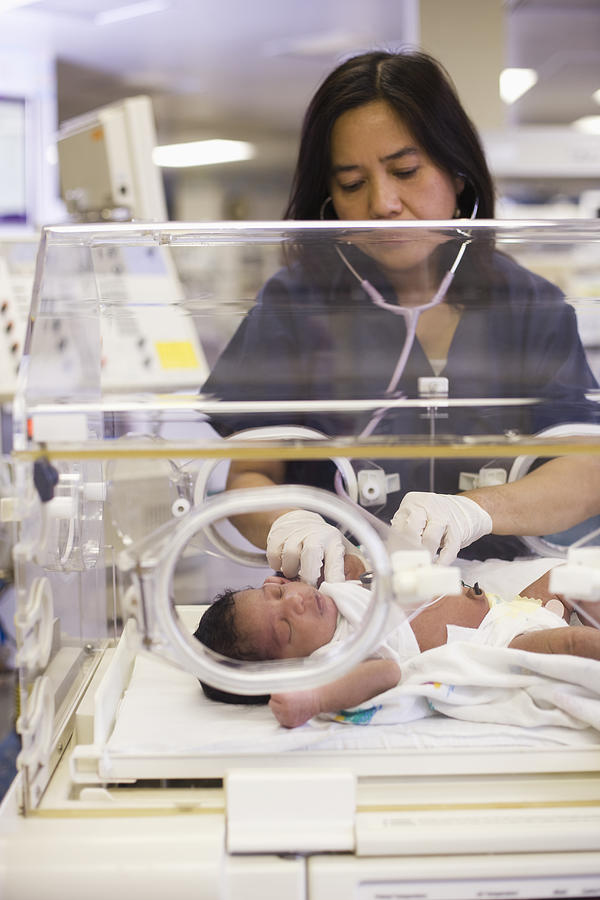 Nurse helping newborn baby in hospital nursery #1 Photograph by ER Productions Limited