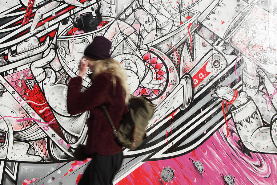 NYC young woman walking past How Nosm street art mural #1 Photograph by CribbVisuals