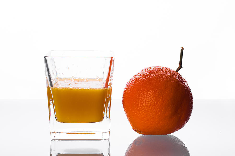 Orange juice pouring into glass #1 Photograph by MichalDziedziak