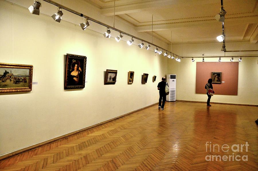 Painting artworks hang on wall while visitors view Adjara  Art Museum Batumi Georgia #2 Photograph by Imran Ahmed
