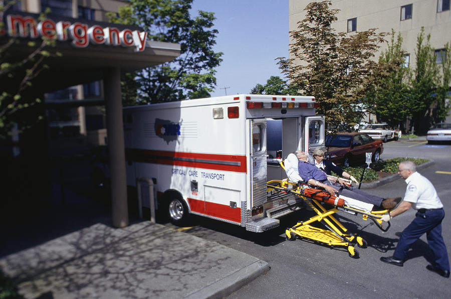 Paramedics taking patient on gurney from ambulance at emergency ward #1 Photograph by Keith Brofsky