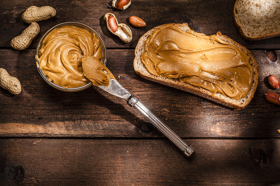 Peanut butter on bread slice shot on rustic wooden table #1 Photograph by Fcafotodigital