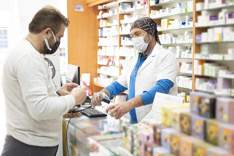 Pharmacist wearing protective hygienic mask and making drug recommendations in modern pharmacy #1 Photograph by Mehmet Hilmi Barcin